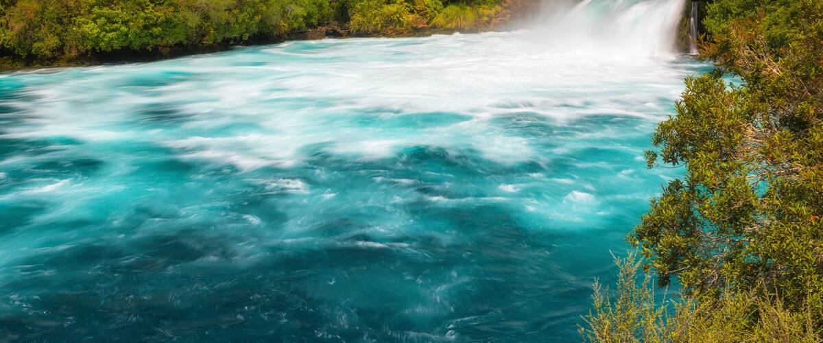 A river with a waterfall surrounded by dense green forest.