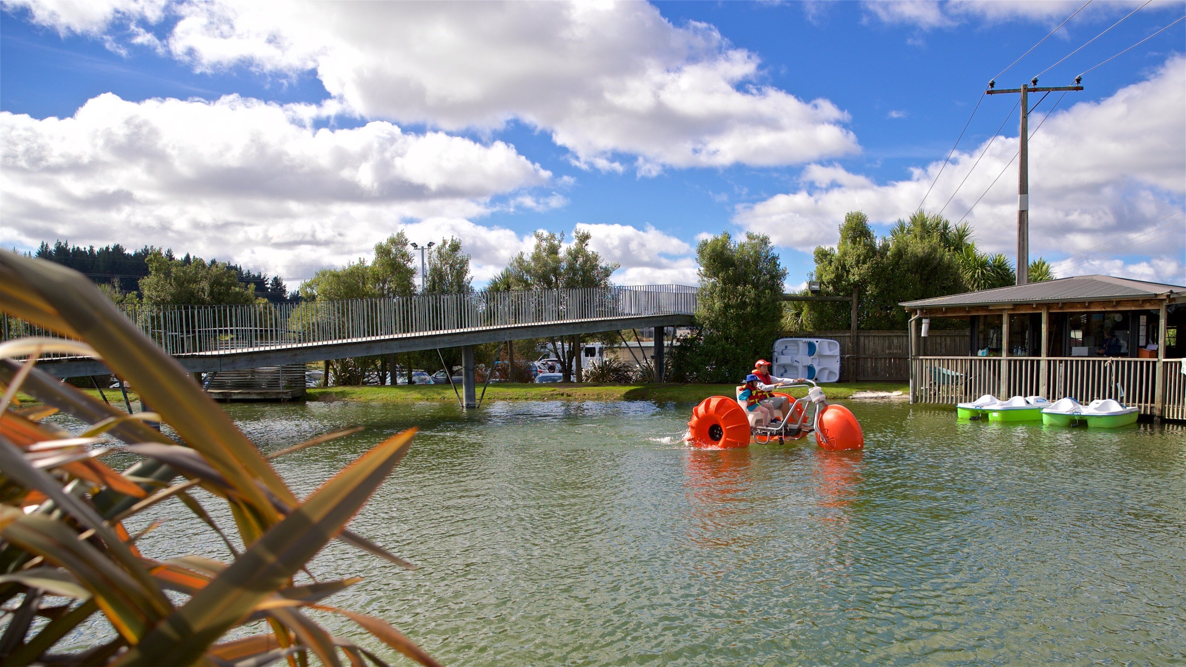 A flooded area with a bridge, paddle boats, and a wooden building.