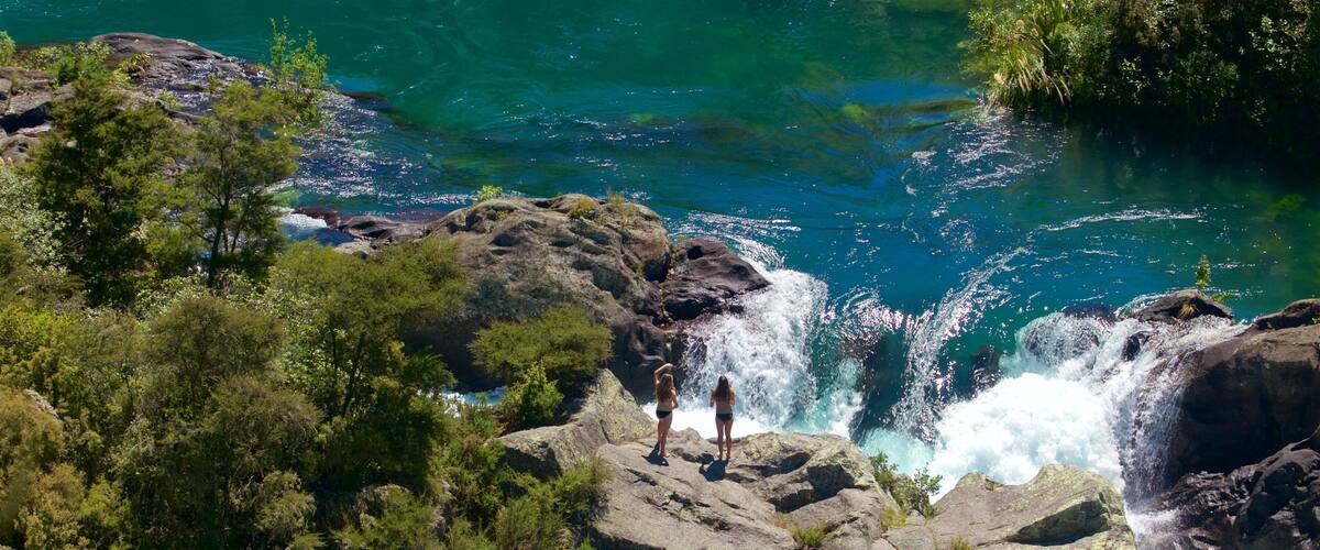 Aratiatia Rapids featuring a river or creek and rapids as well as a small group of people