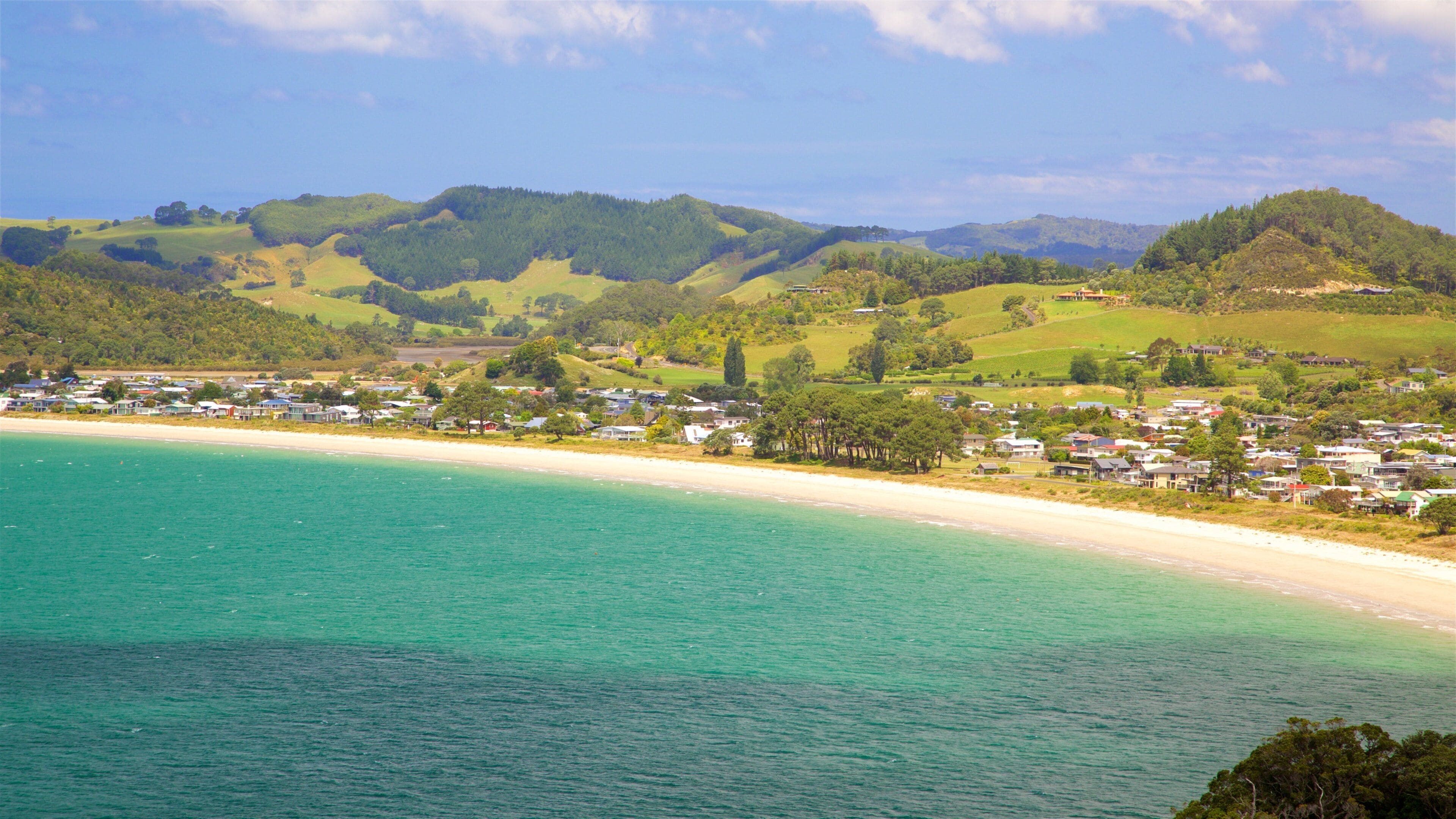 A coastal town with a sandy beach and rolling hills in the background.
