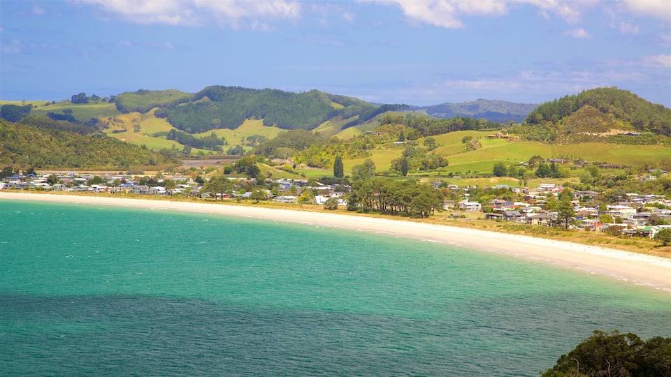 A coastal town with a sandy beach and rolling hills in the background.