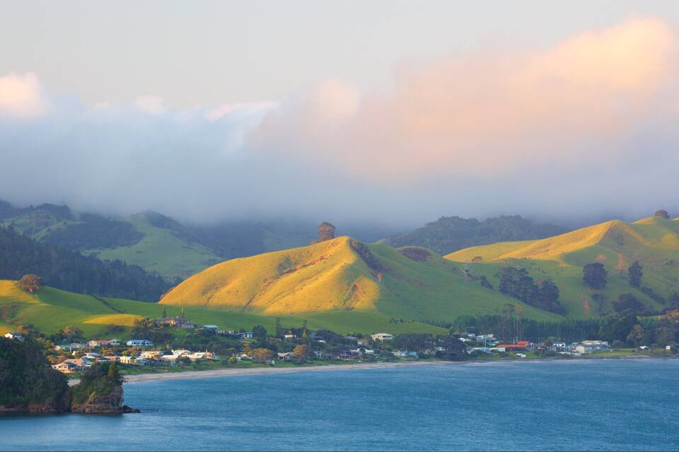 A coastal landscape with rolling hills, a small town, and a body of water.