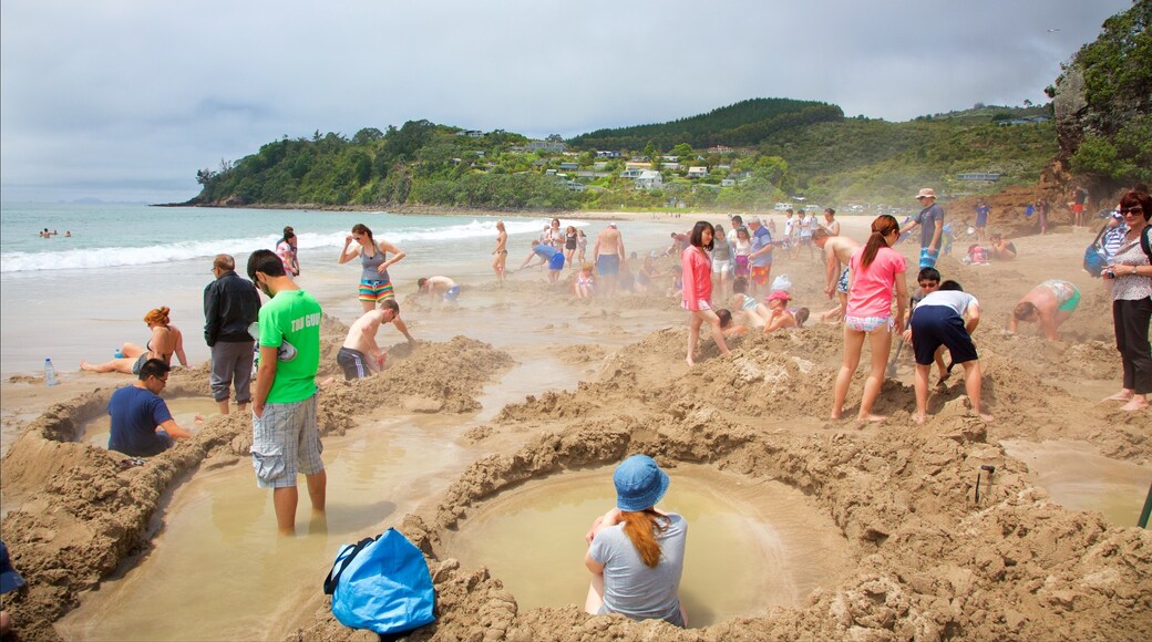 Hot Water Beach som omfatter en sandstrand, en kystby og svømning