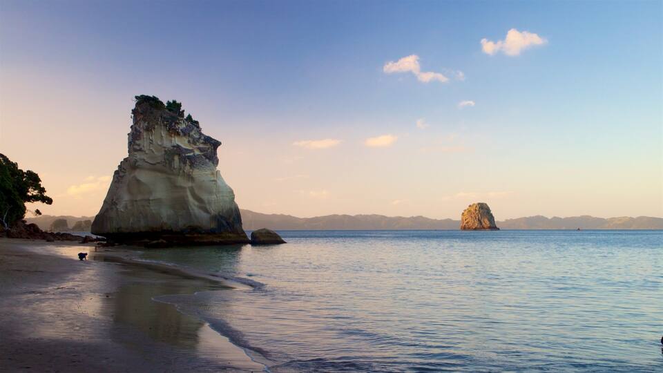 A coastal landscape with a prominent rock formation and a smaller island in the distance.