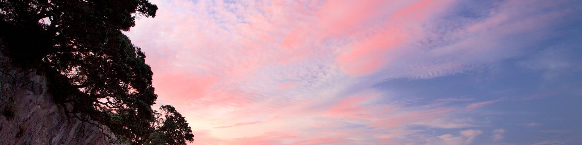 Hahei Beach featuring a sunset, a bay or harbour and a beach