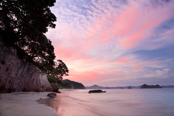 Hahei Beach featuring a sunset, a bay or harbour and a beach