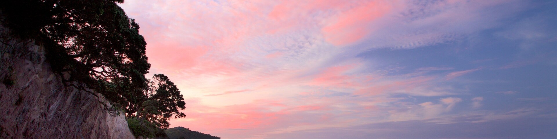 Hahei Beach ofreciendo una bahía o un puerto, una playa de arena y un atardecer