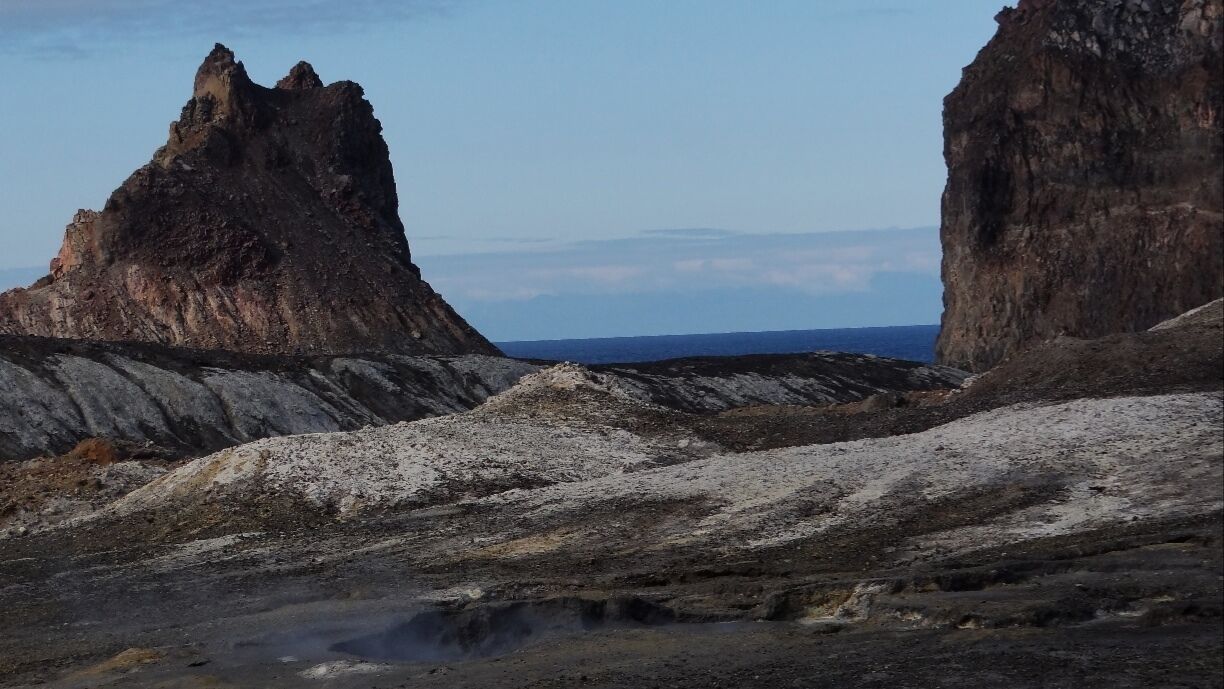 The landscape is barren but full of rich earth and mineral colors that really stand out against the blue ocean.