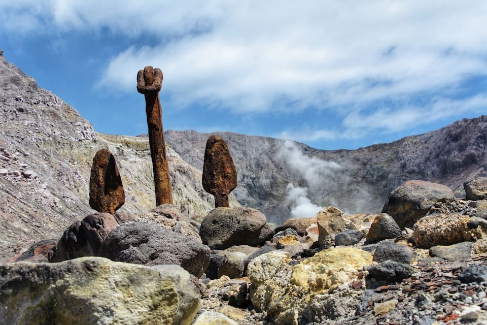 A rocky landscape with prominent vertical rock formations and a steam vent.