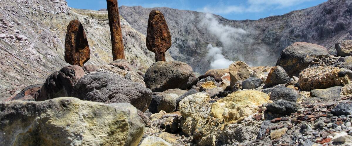 A rocky landscape with prominent vertical rock formations and a steam vent.