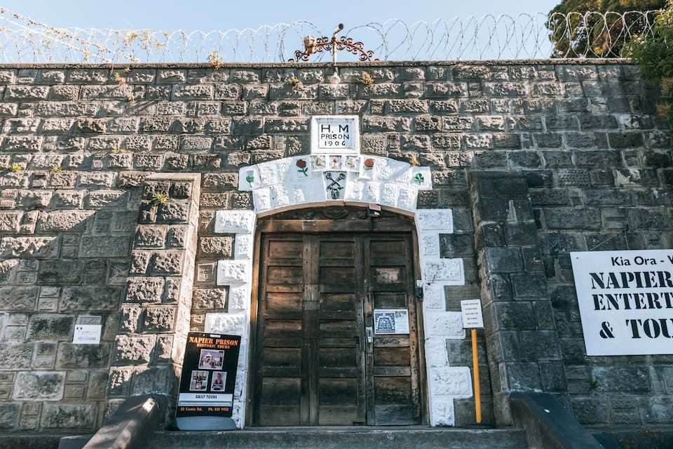 Entrada de pedra a una presó, amb un cartell que anuncia entreteniment i visites a la presó de Napier.