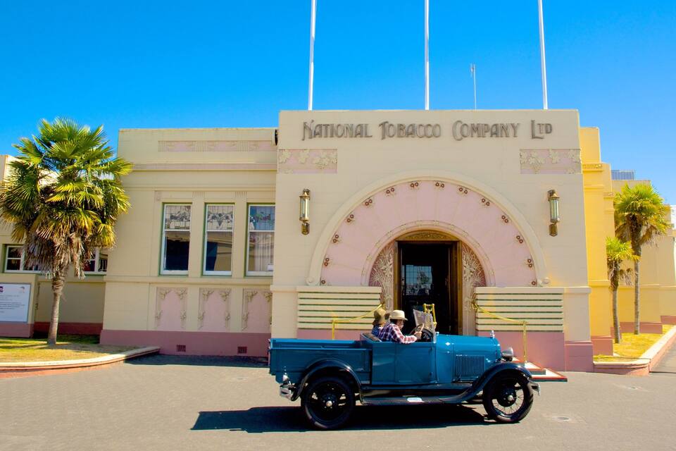 Un camión azul antiguo estacionado frente al edificio de la Compañía Nacional de Tabaco Ltd.