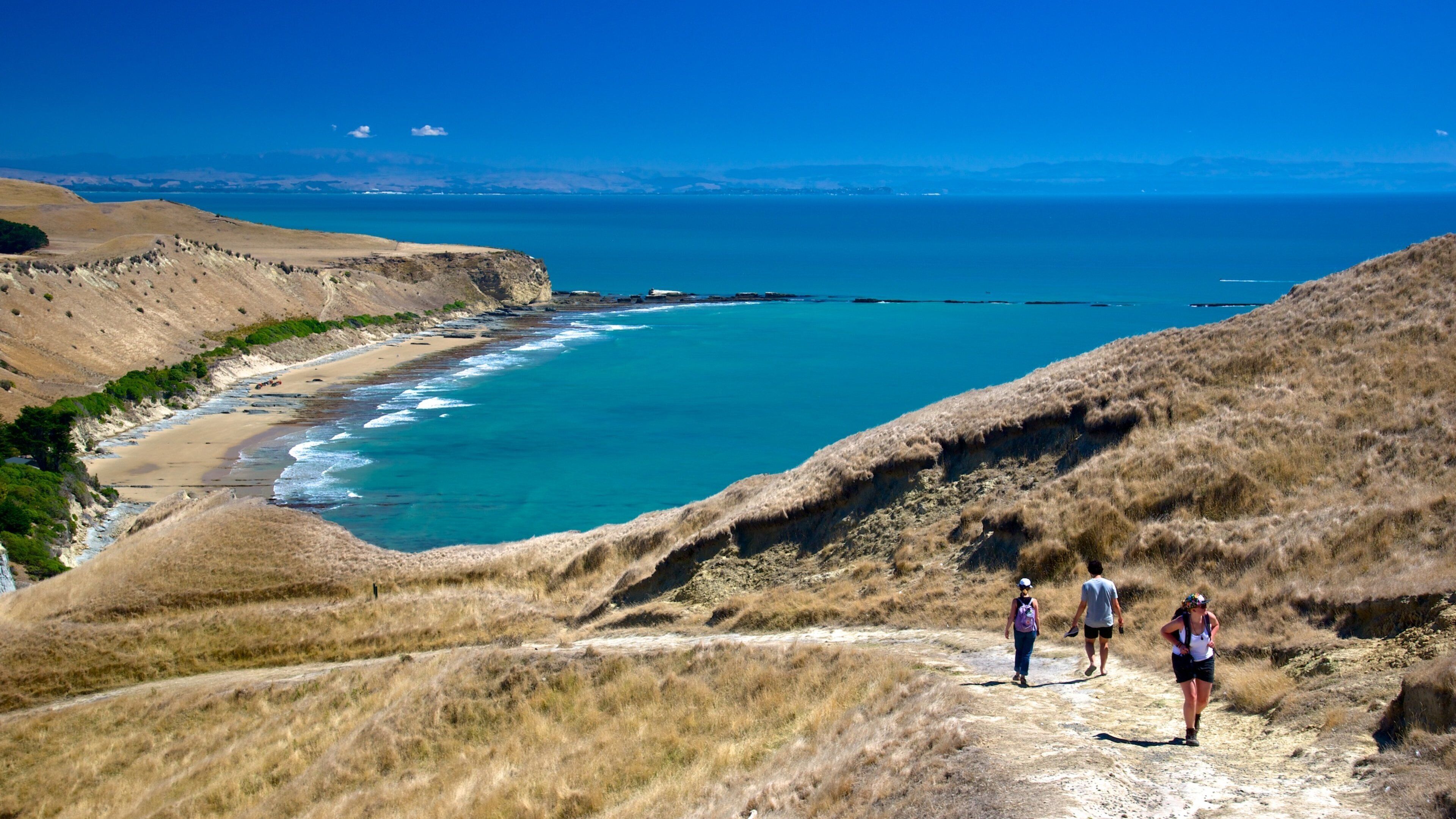 A coastal landscape with a beach, cliffs, and a clear blue sea.