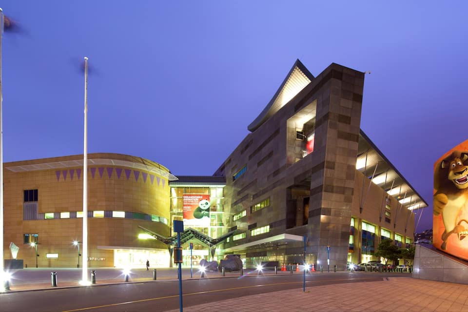 A modern building with a large illuminated sign and a prominent lion statue.
