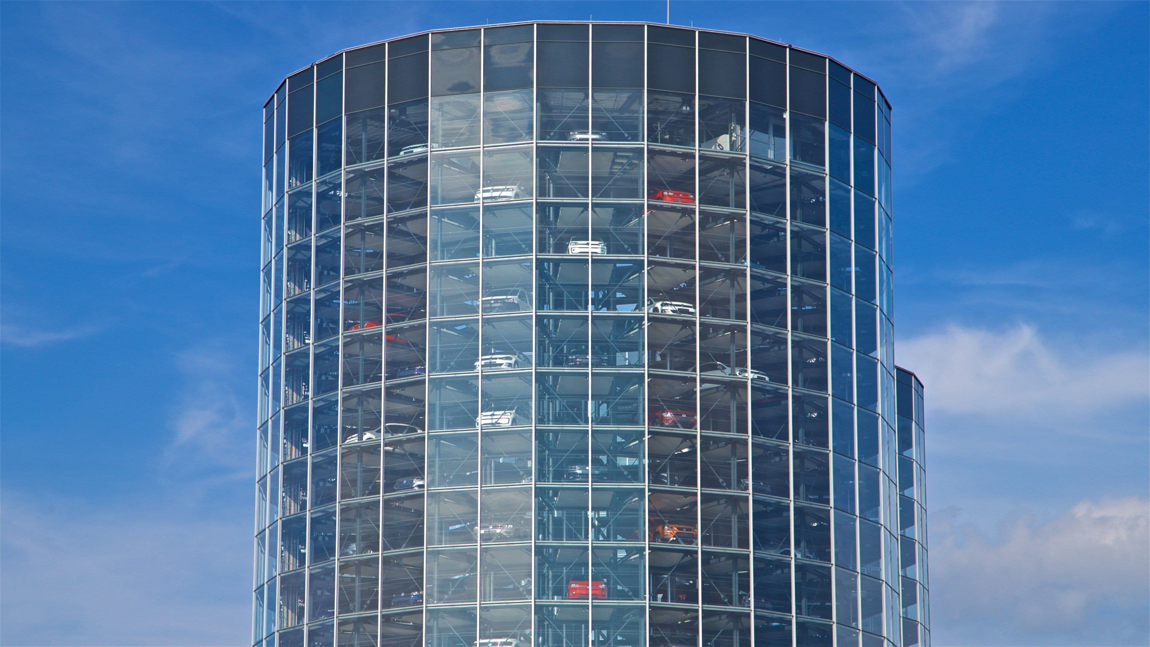 A modern glass building with multiple floors and a curved design.