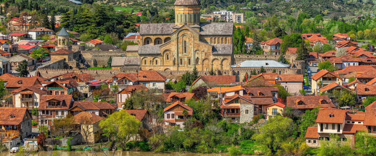 A historic town with a prominent church, a river, and surrounding hills.