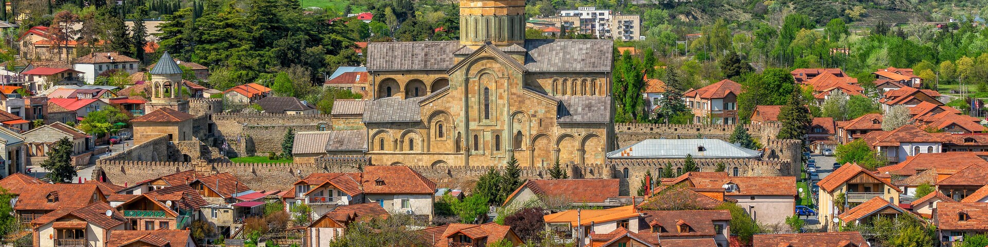 A historic town with a prominent church, a river, and surrounding hills.