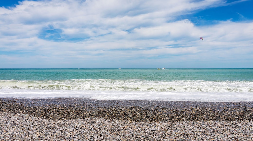 Beautiful empty pebble stone beach in Batumi, Georgia. Boat with paragliding. Bright Summer sunny day, blue water. No people.