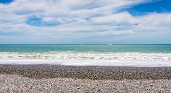 Beautiful empty pebble stone beach in Batumi, Georgia. Boat with paragliding. Bright Summer sunny day, blue water. No people.