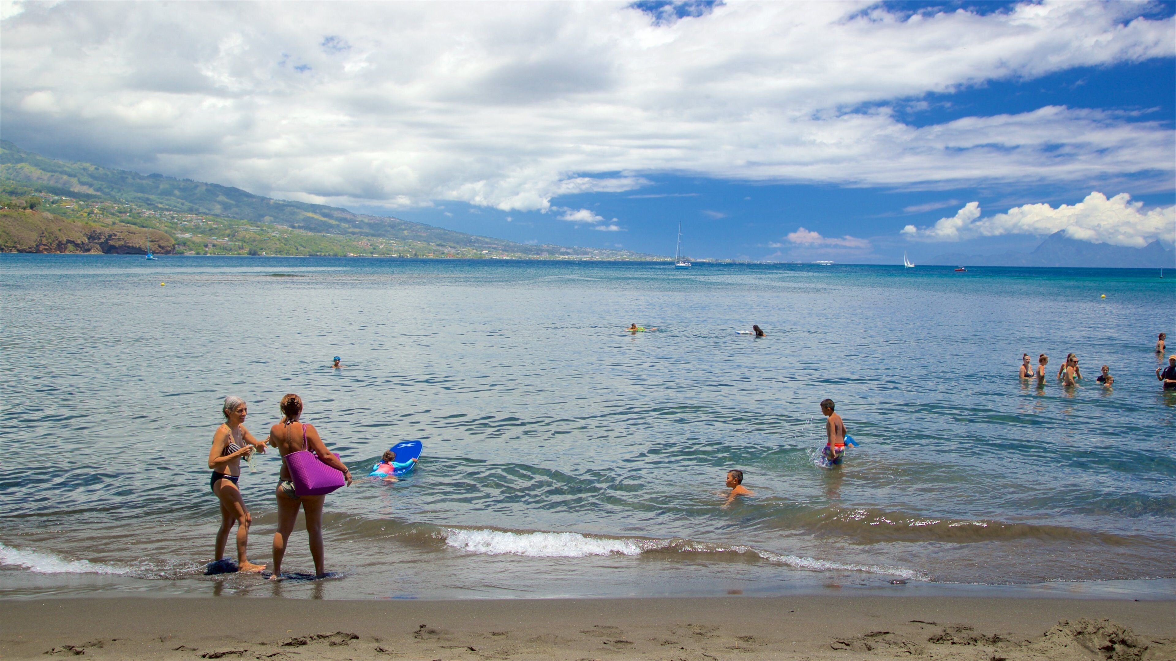 Black Sand Beach featuring general coastal views and swimming as well as a small group of people