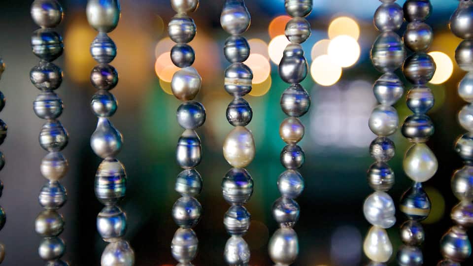 A close-up of shiny, reflective beads with a blurred background of lights.