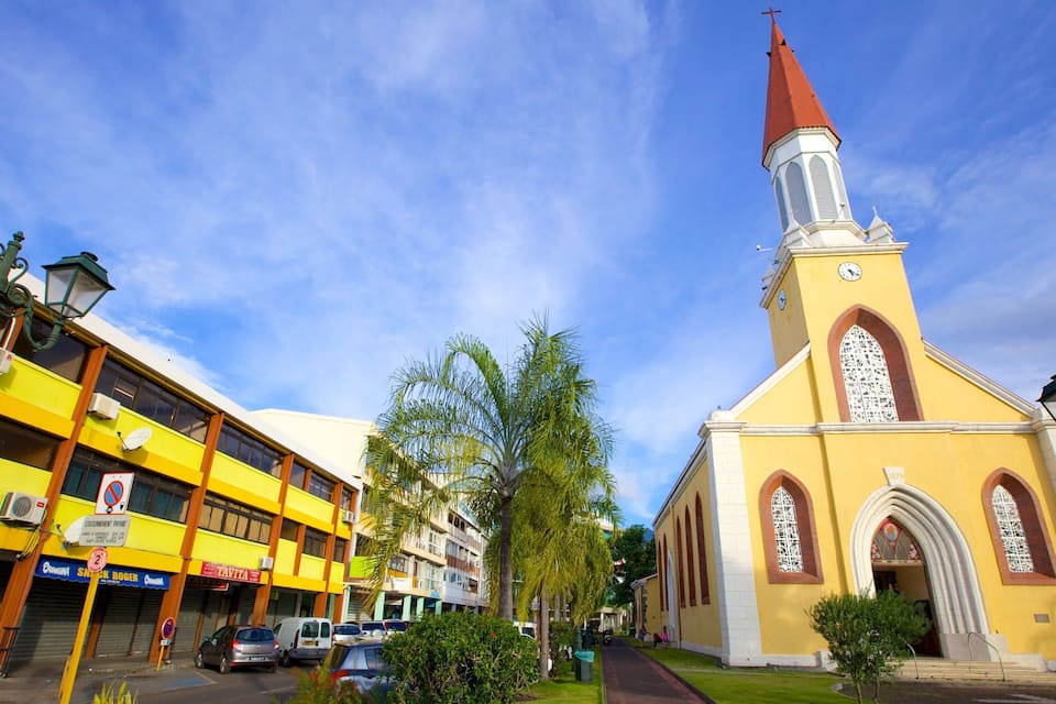 Uma igreja com um campanário vermelho e um edifício amarelo com lojas.