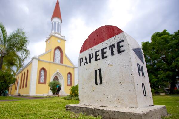 A church with a red steeple and a gravestone labeled "Papeete" in front of it.