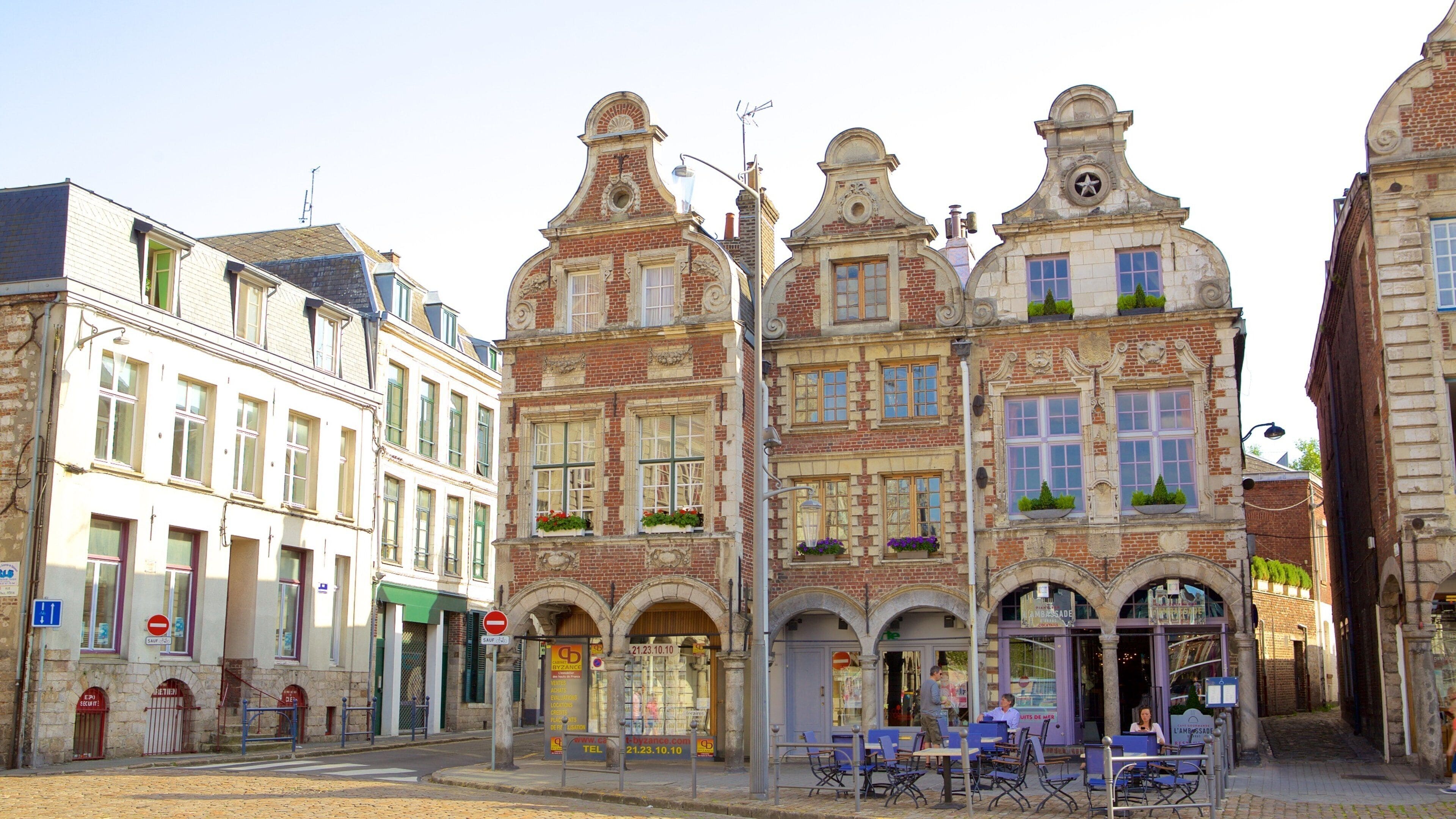 A street with historic European architecture, including buildings with ornate facades and a café with outdoor seating.