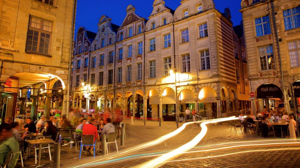 A cobblestone street with historic buildings and outdoor cafes at dusk.