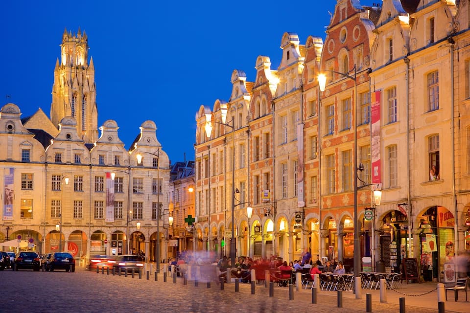 A historic European street at dusk with ornate buildings and a prominent church tower.