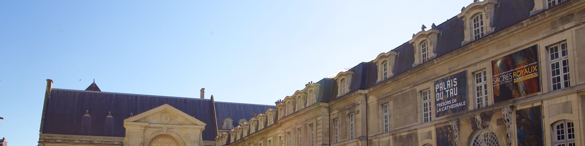 A historic building with a courtyard, featuring a prominent entrance and a large banner.