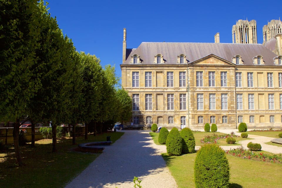 Un grand bâtiment historique à la façade symétrique, doté d’une cour intérieure et d’un jardin magnifiquement entretenu.
