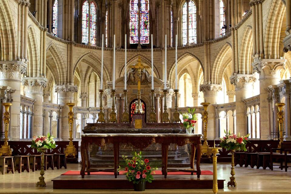 A grand cathedral interior with high vaulted ceilings, stained glass windows, and ornate columns.