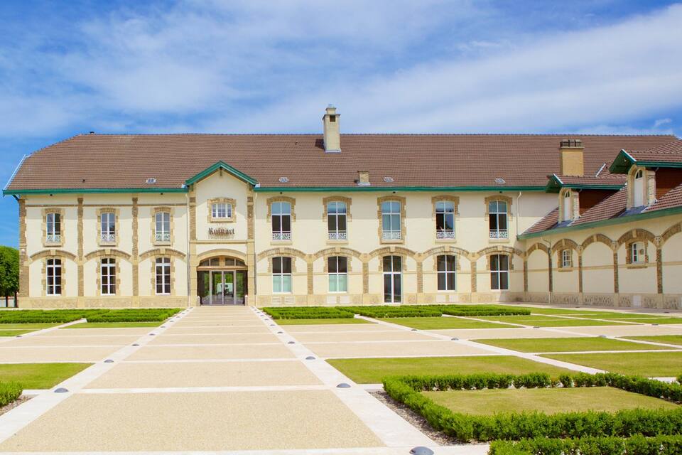 A large, historic building with a symmetrical facade, arched windows, and a central entrance.