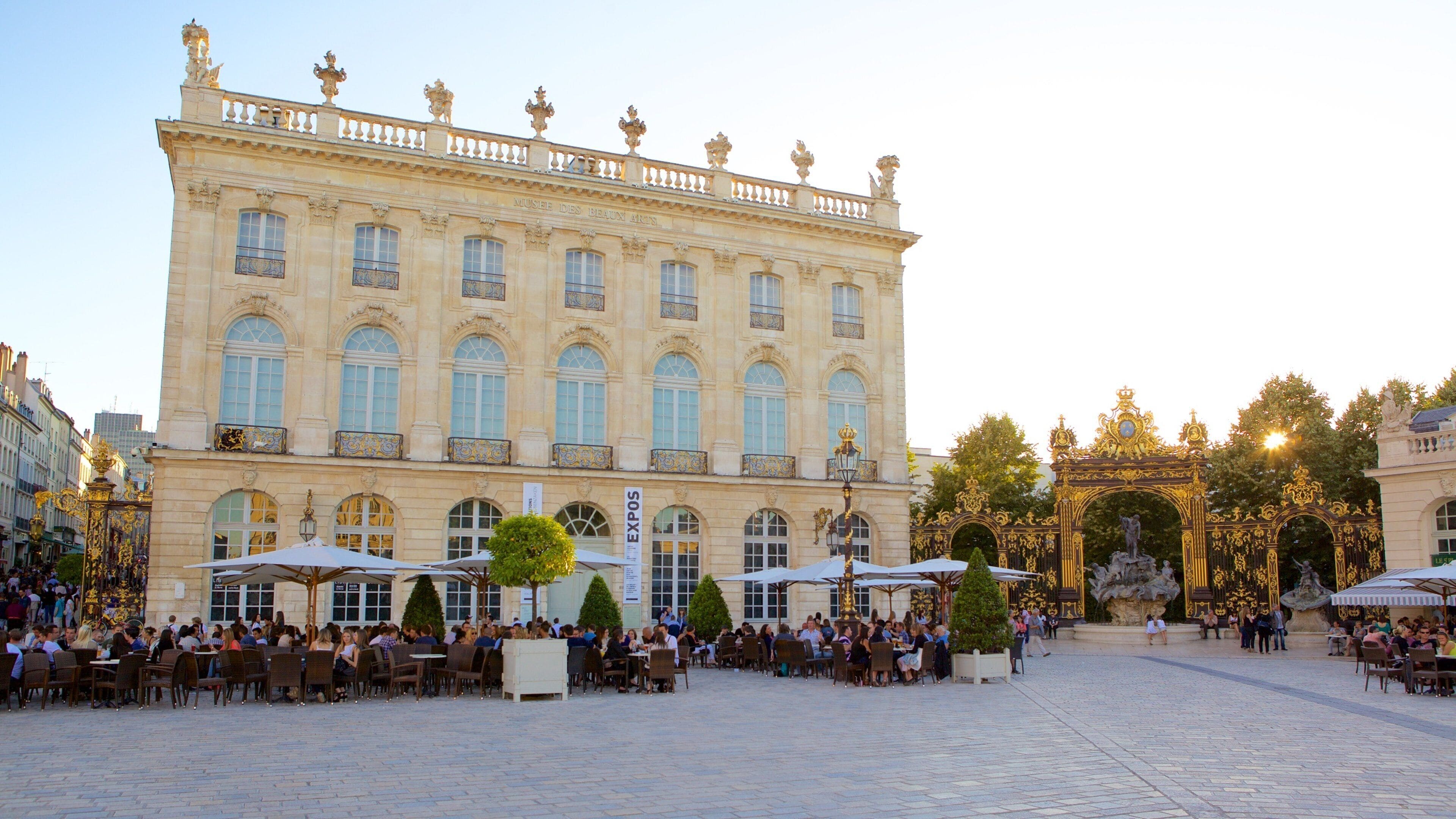 A historic building with ornate balconies and a large open courtyard with outdoor seating.