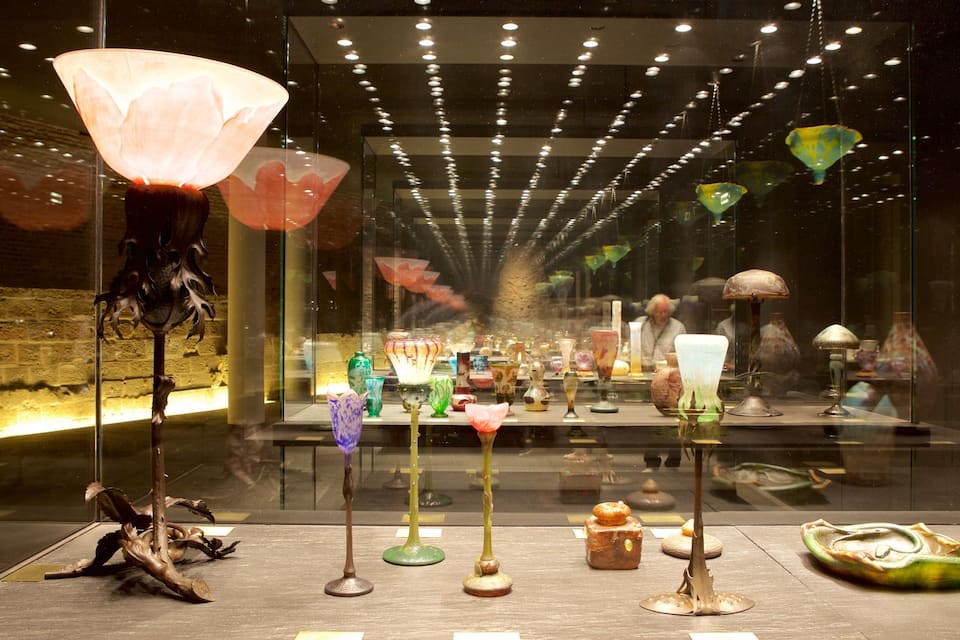Exposição de arte em vidro com diversas esculturas e luminárias coloridas.