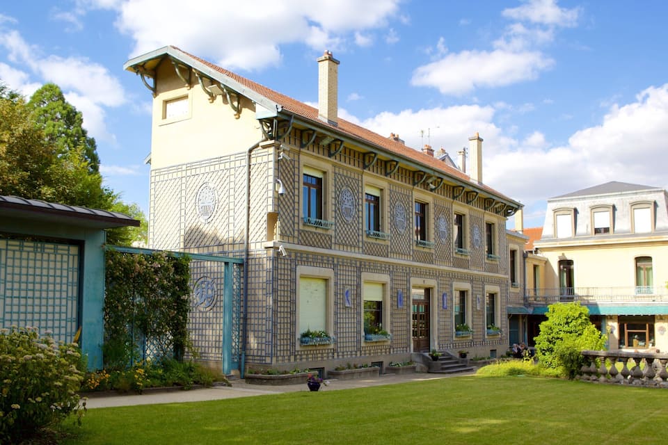 Um edifício histórico com trabalhos em azulejos detalhados e um jardim bem cuidado.