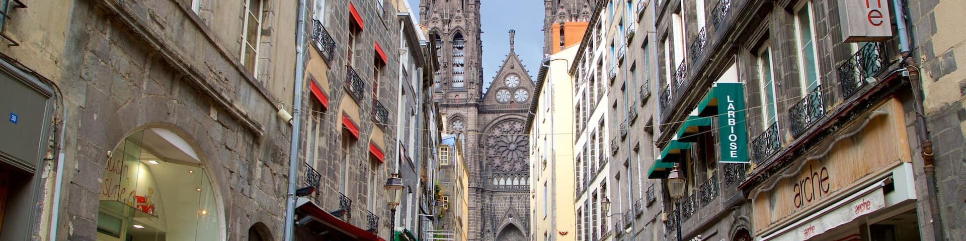 A bustling street with historic buildings, a prominent church spire, and various shops.