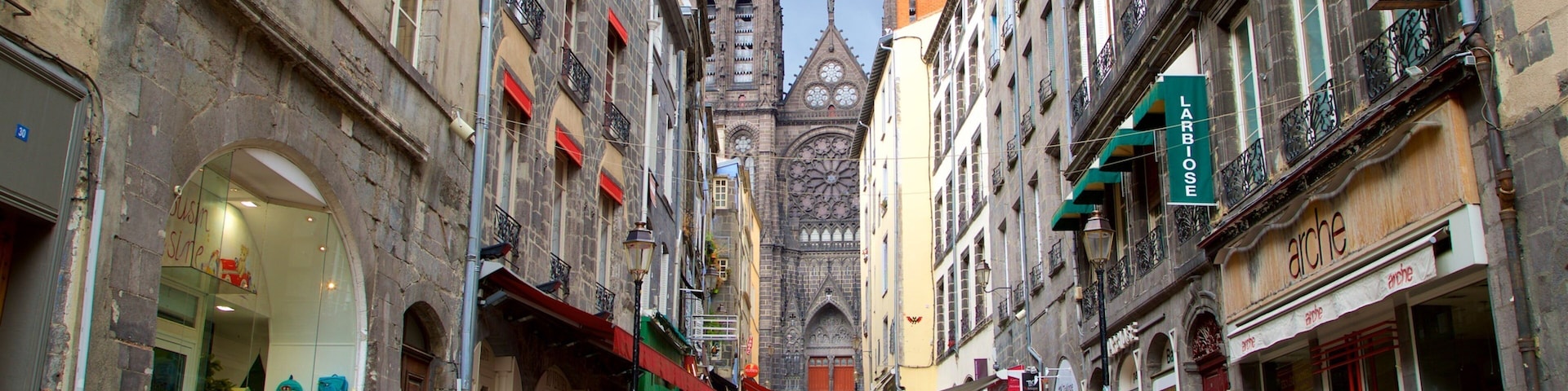 Una calle animada con edificios históricos, una prominente aguja de iglesia y diversas tiendas.