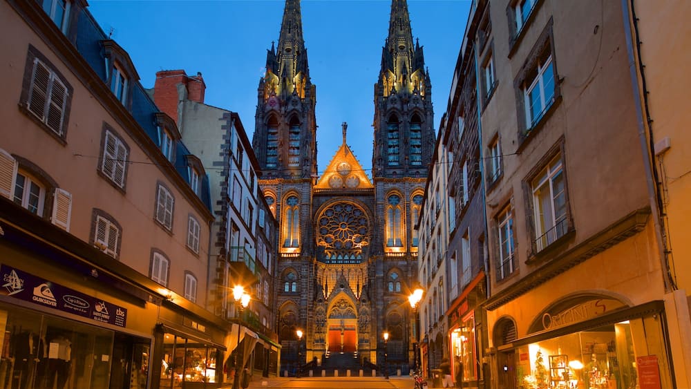 A Gothic cathedral with twin spires, flanked by historic buildings with shop fronts.
