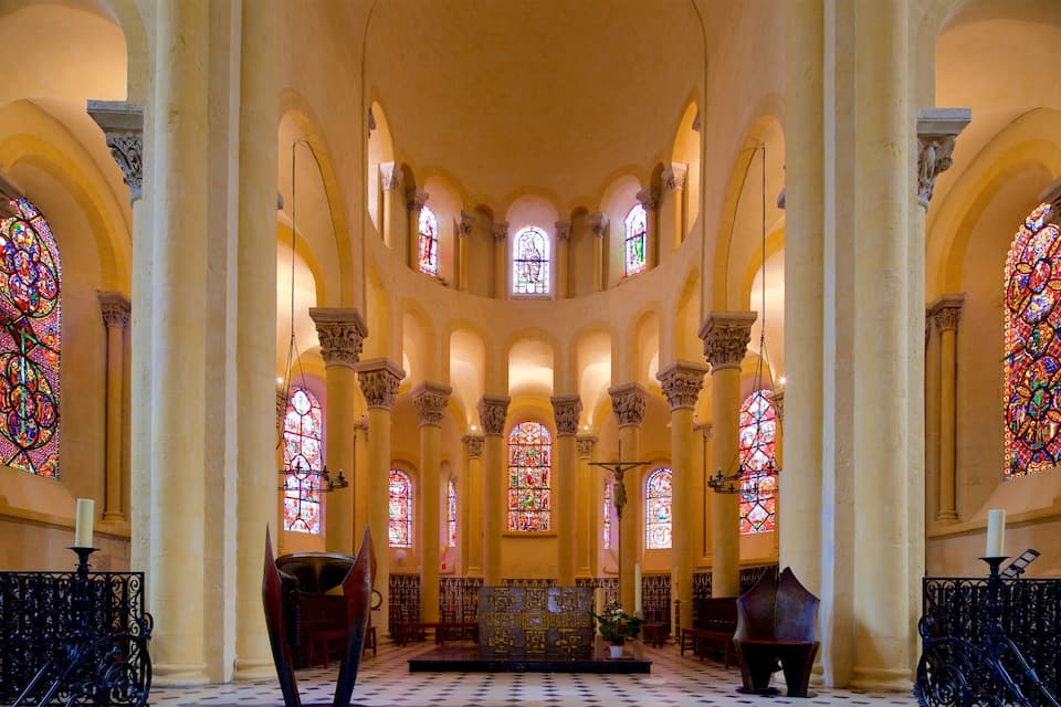 L’intérieur d’une église, avec de hauts plafonds, des fenêtres en arc de cercle et des vitraux.