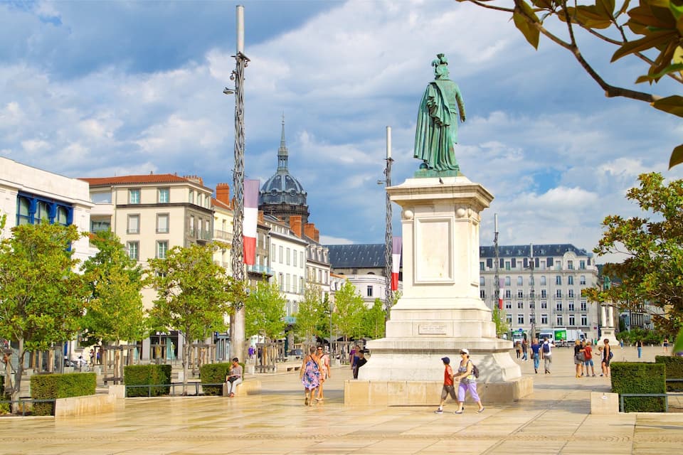 Une place publique avec une statue, des bâtiments et des arbres.