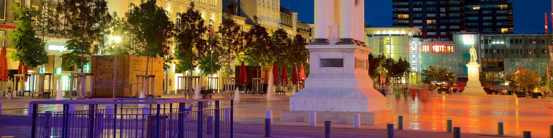 A city square with a prominent statue, historic buildings, and modern architecture.