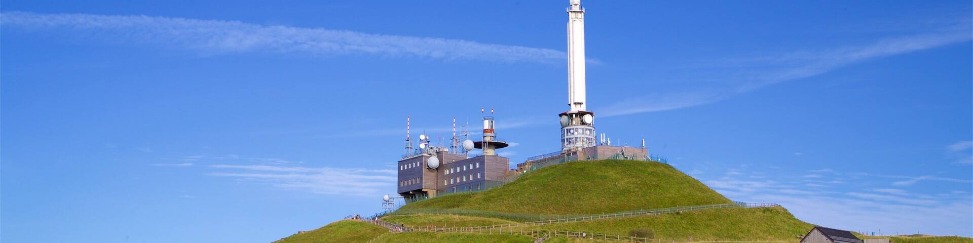 Una colina con una torre blanca alta y un edificio con antenas.