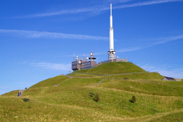 Une colline surmontée d’une haute tour blanche et d’un bâtiment doté d’antennes.