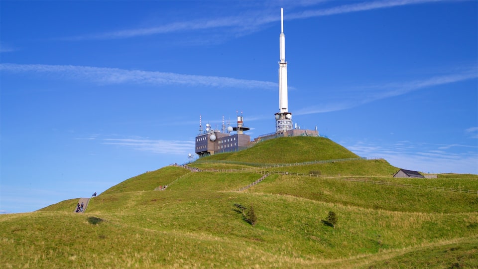 A hill with a tall white tower and a building with antennas.