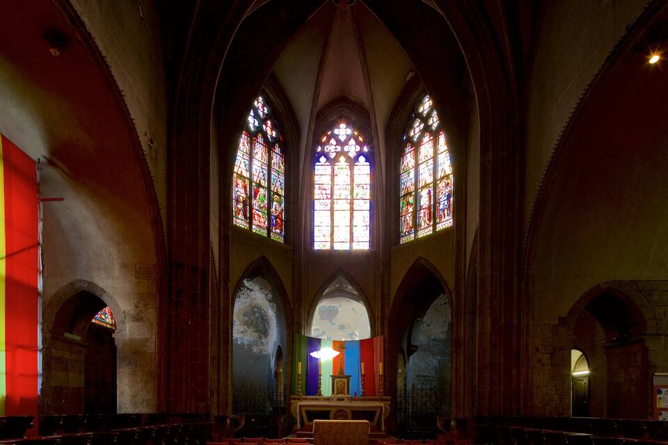 A church interior with stained glass windows, arched ceilings, and a central altar.