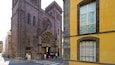A historic church with intricate Gothic architecture and a yellow building with a balcony.