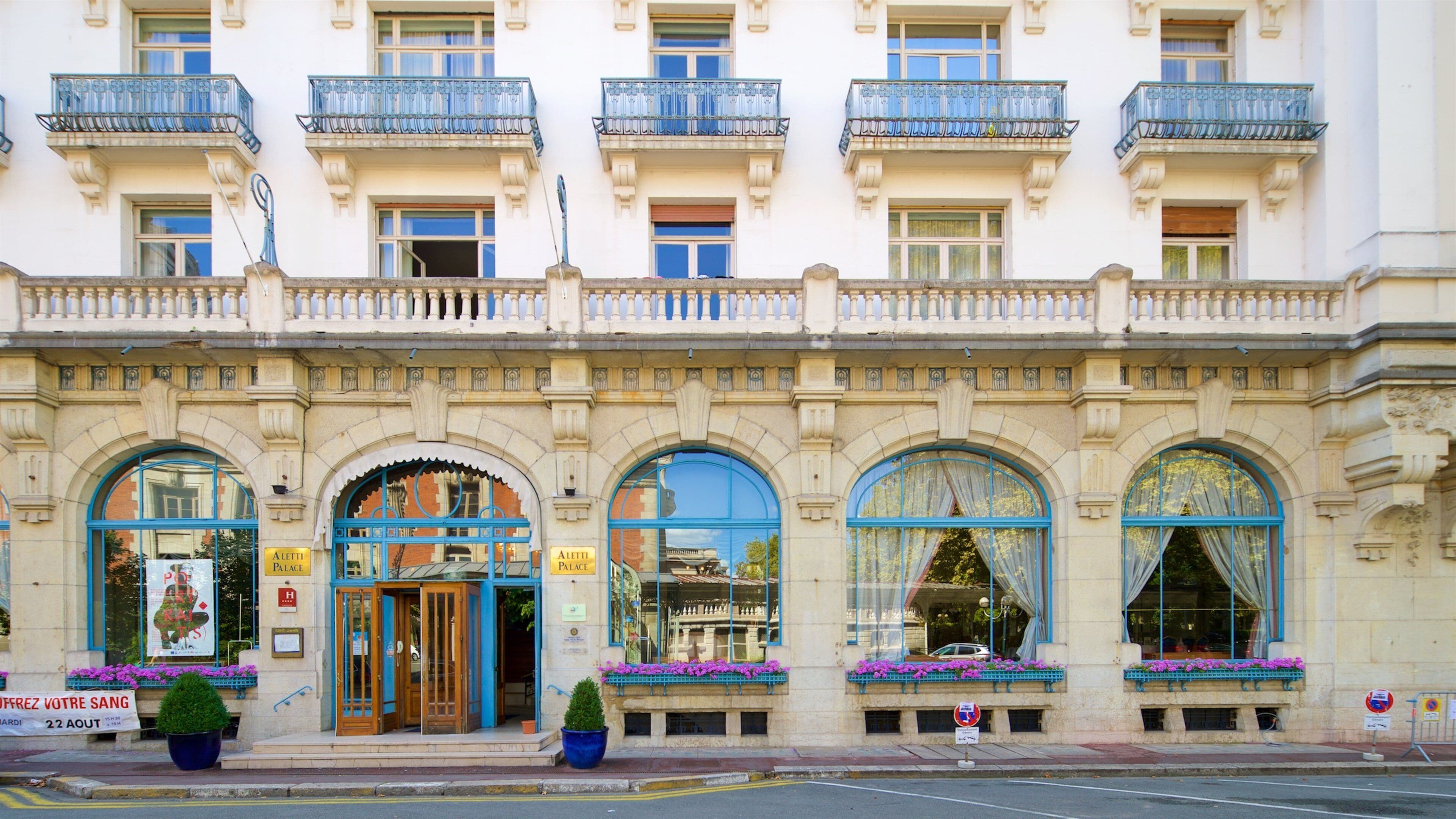 A historic building with ornate balconies, large arched windows, and flower boxes.