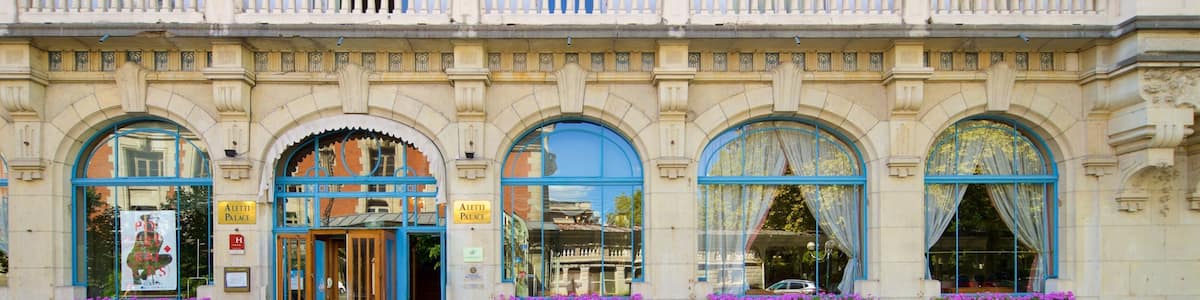 A historic building with ornate balconies, large arched windows, and flower boxes.